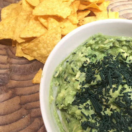 Un bol de guacamole avec des chips et de la spiruline