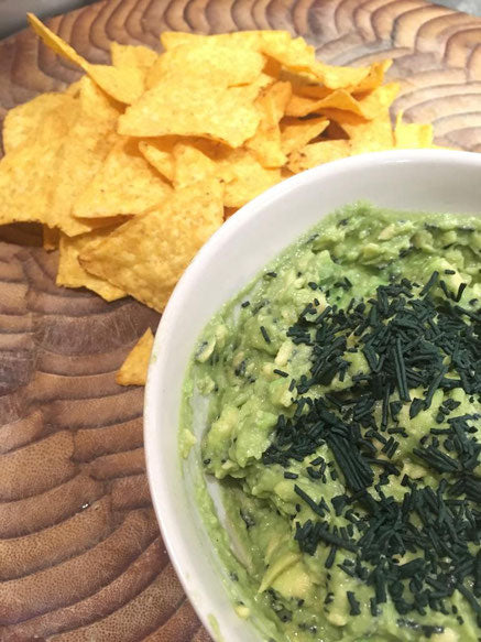 Un bol de guacamole avec des chips et de la spiruline