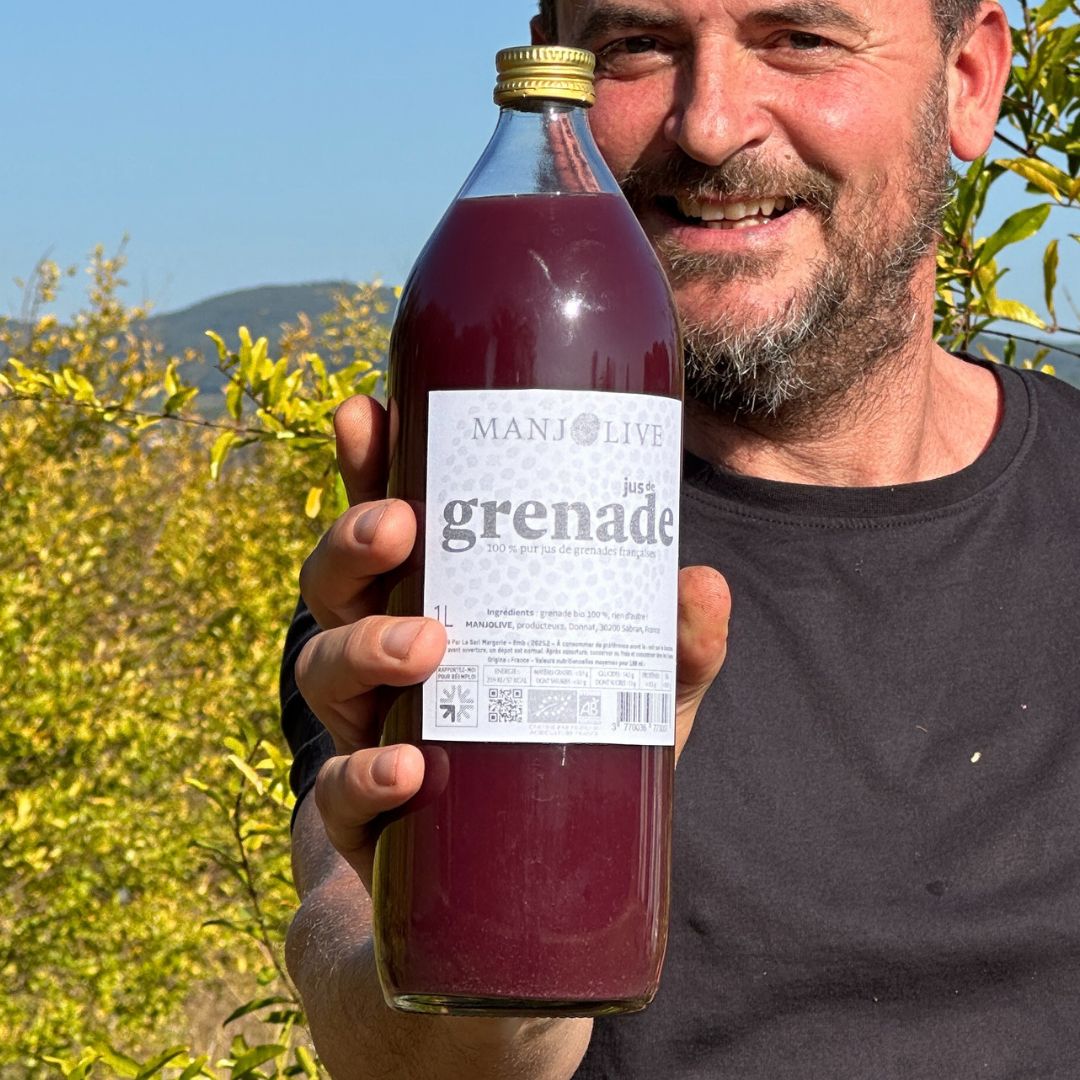 Un homme tient une bouteille de jus de grenade bio