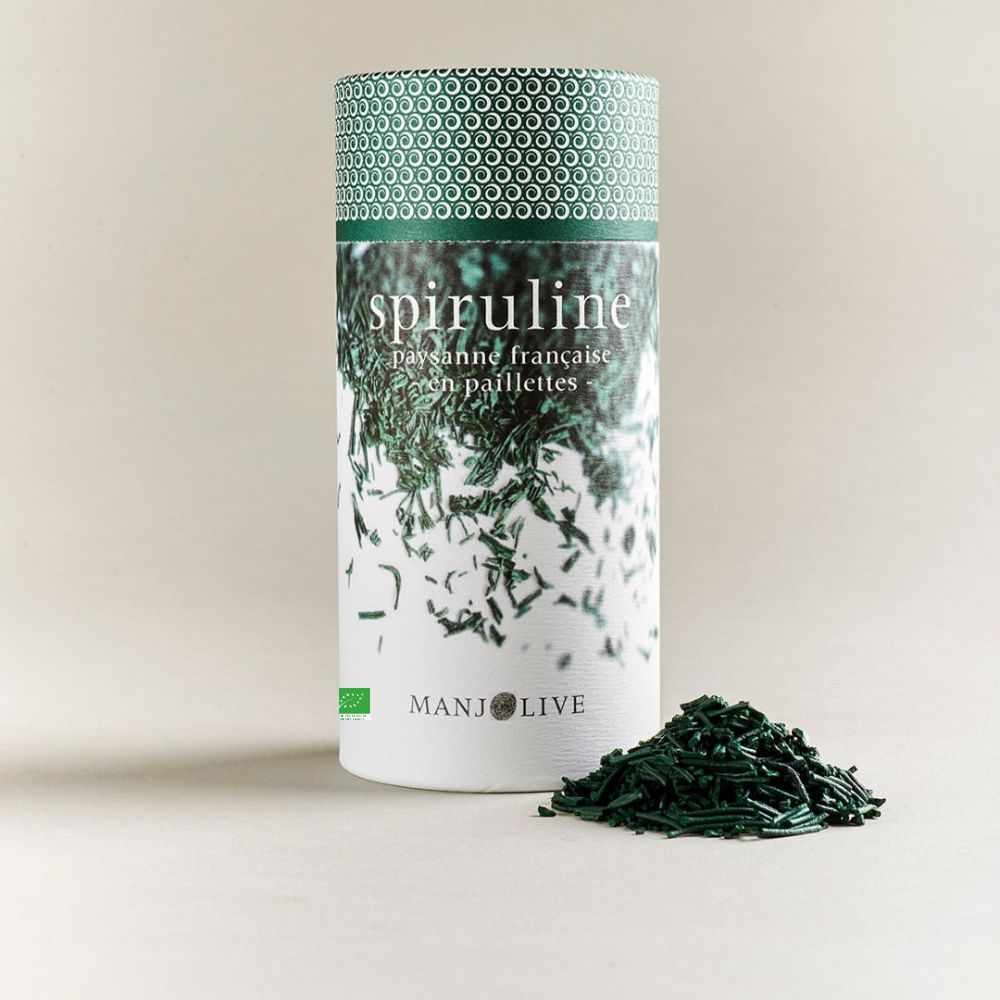 Une boite de spiruline bio de Manjolive avec quelques paillettes sorties