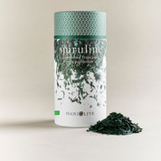 Une boite de spiruline bio de Manjolive avec quelques paillettes sorties