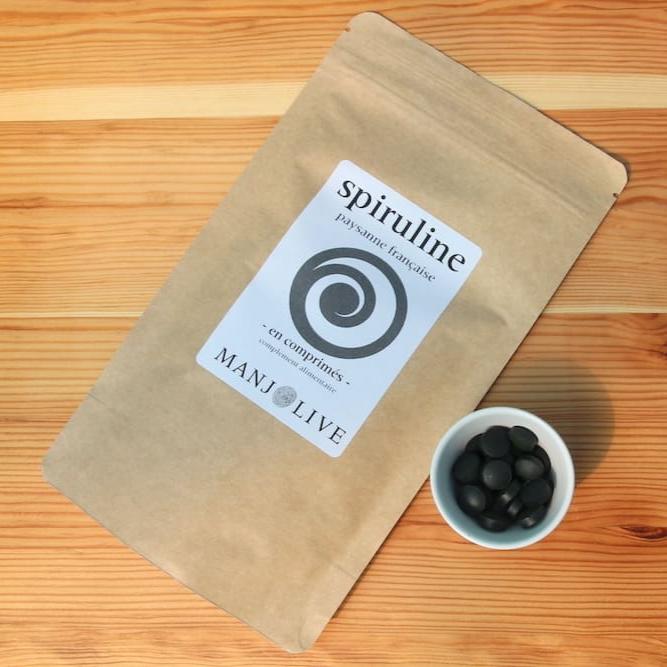 Un sachet de spiruline en comprimé posé avec des comprimés dans un récipient